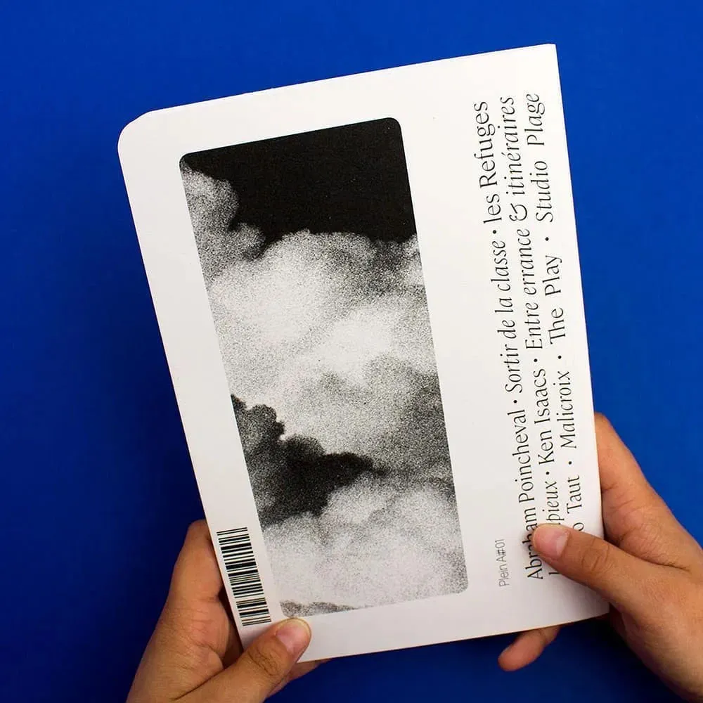 Livre tenu fermé, de dos, un détail de photo de nuages en noir et blanc, avec du grain et un noir très profond dans une cartouche verticale. À coté, la liste des articles et auteurs, écrits dans une typographie à empattements, élégante et souple. Ce texte est disposé verticalement.